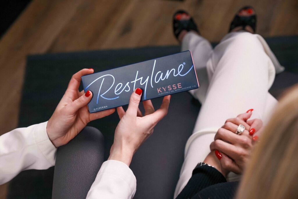 A provider shows a female patient a box holding Restalyne Kysse dermal filler. This is one of the premier fillers used as the best lip filler in Scottsdale.