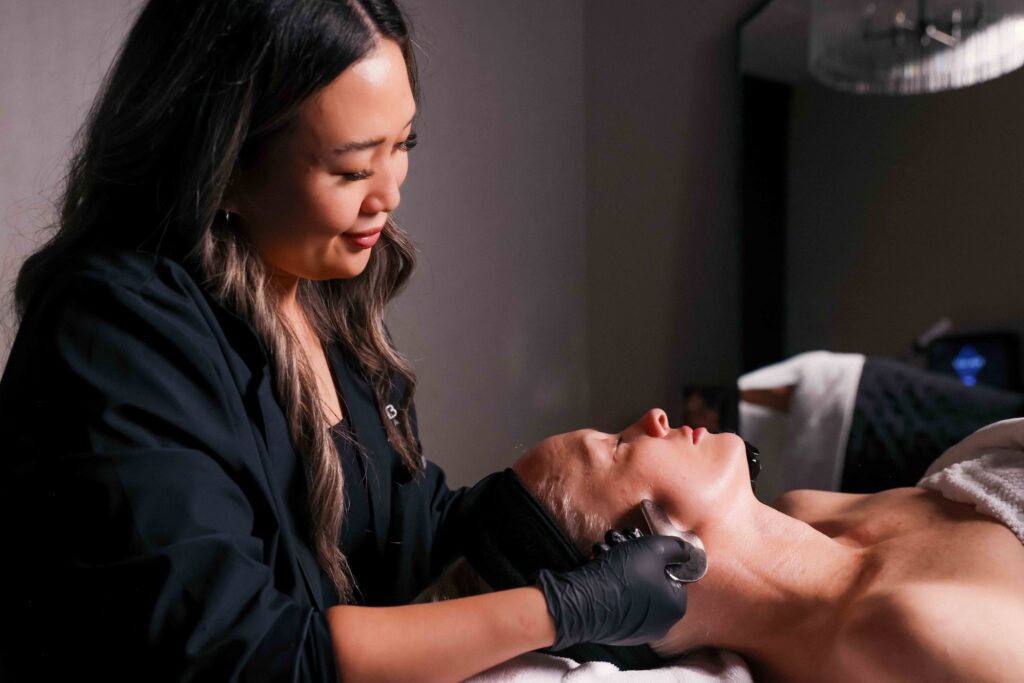 A Look Lab provider, wearing a black lab shirt and black surgical gloves, performs a signature facial on a relaxed patients. This facial supports the results of the best Hydrafacial in Winter Park.